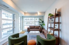 Edmonton apartment for rent - A living room with a green chair, a brown couch, and a wooden shelf.