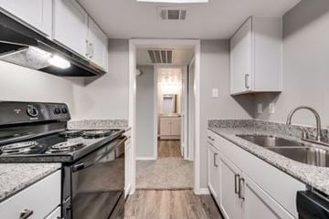 Farmers Branch apartment for rent - A kitchen with a black stove top oven and white cabinets.