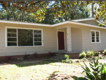 Jackson house for rent - A small house with a red door and white trim is surrounded by greenery.