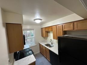 Washington apartment for rent - A kitchen with black appliances and wooden cabinets.