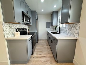 Torrance apartment for rent - A kitchen with grey cabinets and a white tile backsplash.