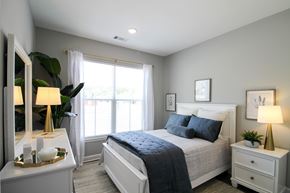 Little Rock house for rent - A bedroom with a large bed, a nightstand with a lamp, and a dresser with a mirror.