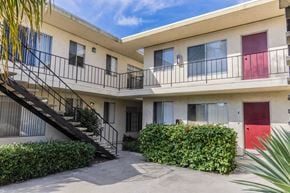 San Diego apartment for rent - A building with a red door and a balcony with a black railing.