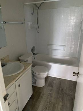 San Diego apartment for rent - A white toilet sits in a bathroom next to a sink and bathtub.