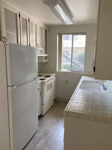San Diego apartment for rent - A kitchen with a white refrigerator, oven, and sink.