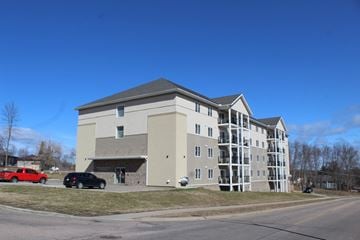 Pembroke apartment for rent - A large building with a parking lot in front.
