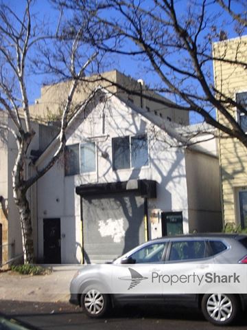 Astoria apartment for rent - A silver car with PropertyShark written on the side is parked in front of a white building.