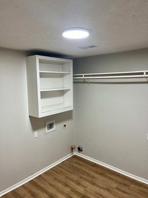 Victoria house for rent - A white cabinet with three shelves is mounted on a wall with a whiteboard and a light fixture above it.