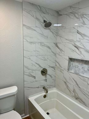 Victoria house for rent - A white toilet sits next to a marble tile shower.