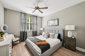 Pompano Beach apartment for rent - A bedroom with a large bed, a ceiling fan, and a nightstand with a lamp.