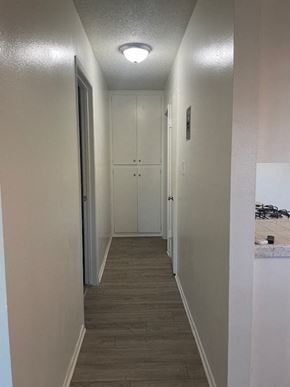 Santa Ana apartment for rent - A long hallway with white walls and wood flooring.