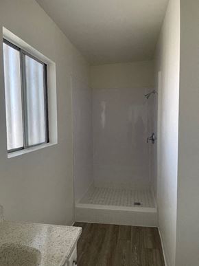 Santa Ana apartment for rent - A white bathroom with a window and a walk-in shower.