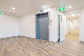 Calgary apartment for rent - A hallway with a blue door and a green exit sign above it.
