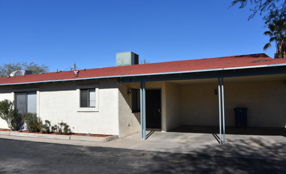 Tucson apartment for rent - A white building with a red roof and a blue trash can in front.