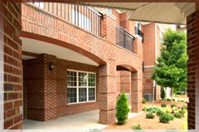 Raleigh apartment for rent - A red brick house with a balcony and a tree in the front yard.