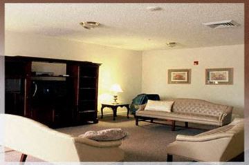 Raleigh apartment for rent - A living room with a couch, chair, ottoman, and lamp.