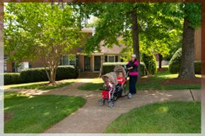 Raleigh apartment for rent - A woman with a baby in a stroller is walking in front of a house.