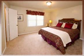Raleigh apartment for rent - A bedroom with a large bed and a window with red curtains.