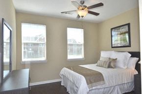 Raleigh apartment for rent - A bedroom with a bed, a ceiling fan, and two windows.