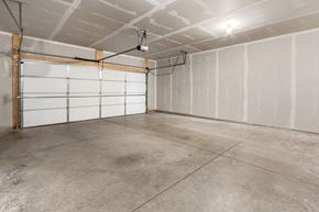 Sioux Falls house for rent - A spacious garage with a white door and concrete floor.