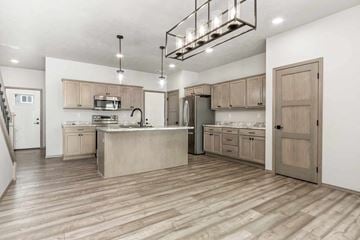 Sioux Falls house for rent - A kitchen with wooden floors and a mix of white and brown cabinetry.