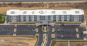 Greeley apartment for rent - A large building with a parking lot in front of it.