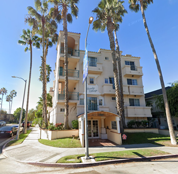 Los Angeles apartment for rent - A white building with a balcony and palm trees in front.