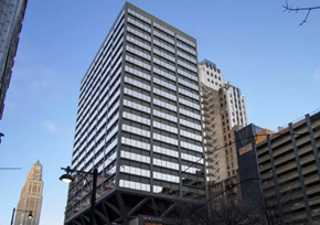 Kansas City apartment for rent - A tall building with many windows stands in front of a skyline.