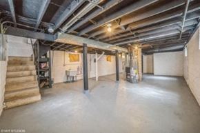 Gary house for rent - A spacious basement with concrete floors and exposed pipes.