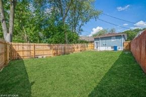 Gary house for rent - A backyard with a wooden fence and a green lawn.