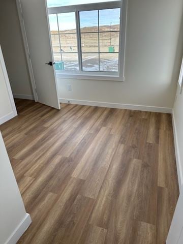 Cochrane house for rent - A room with a wooden floor and a window overlooking a parking lot.