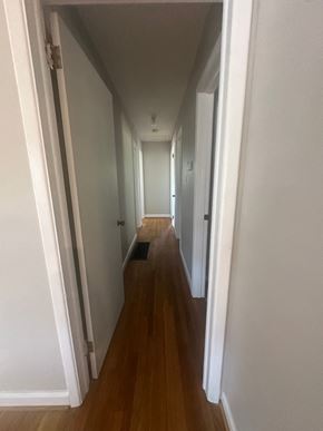 Fayetteville house for rent - A long hallway with white walls and wood floors.