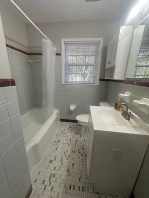 Fayetteville house for rent - A white toilet is in a bathroom with a white sink and a white bathtub.