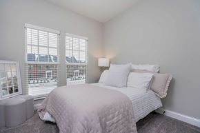 Lewis Center apartment for rent - A bedroom with a large bed and a window overlooking a cityscape.
