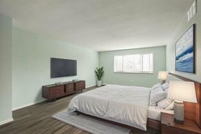 Lakewood apartment for rent - A bedroom with a bed, nightstand, and a plant.