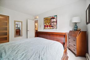 Montréal apartment for rent - A bedroom with a bed, dresser, and a painting on the wall.