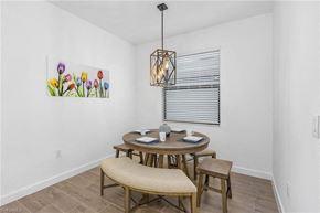 Estero house for rent - A dining room with a table set for two and a painting of flowers on the wall.