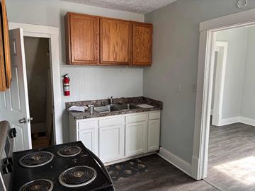 Akron apartment for rent - A kitchen with a black stove top oven and wooden cabinets.