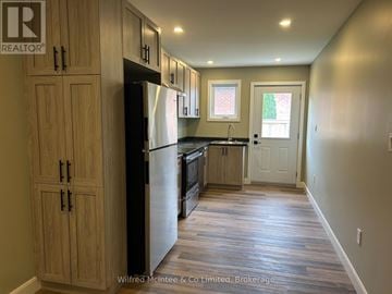 Arran-Elderslie townhouse for rent - A kitchen with wooden cabinets and a black refrigerator.