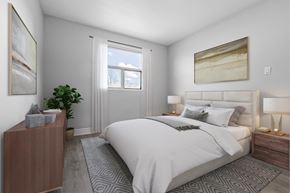 Welland apartment for rent - A bedroom with a large bed, a nightstand, and a plant.