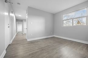 Welland apartment for rent - A spacious room with wood flooring and a large window.