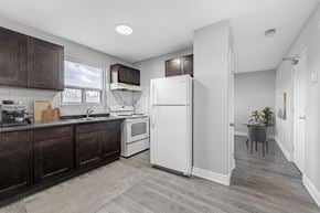 Welland apartment for rent - A kitchen with a white refrigerator and brown cabinets.