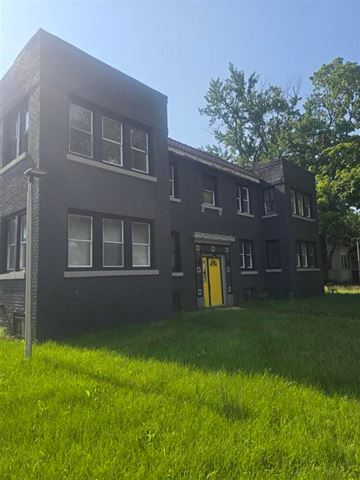 Rockford apartment for rent - A black building with a yellow door and windows.
