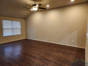 Longview apartment for rent - A room with a ceiling fan and wooden flooring.