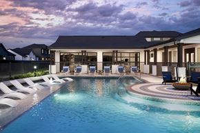 Hutto apartment for rent - A large swimming pool in front of a house with a sunset in the background.