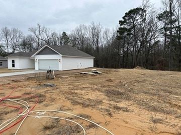 Benton house for rent - A white building with a grey roof is surrounded by bare trees and a dirt field.