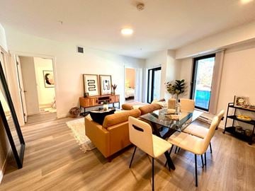Vancouver apartment for rent - A modern living room with a glass table and white chairs.