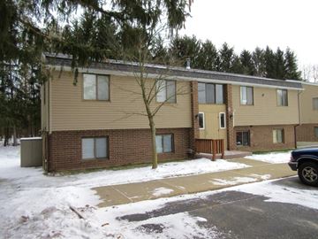 Greenville apartment for rent - A building with a brown and beige exterior is surrounded by snow.