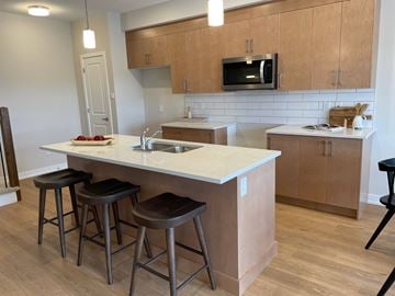 Kanata apartment for rent - A kitchen with a white counter top and brown bar stools.