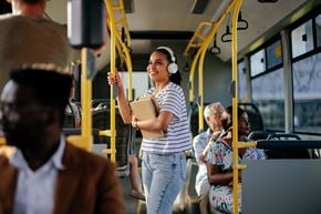 Minneapolis apartment for rent - A woman in a striped shirt is holding onto a pole while riding a bus.